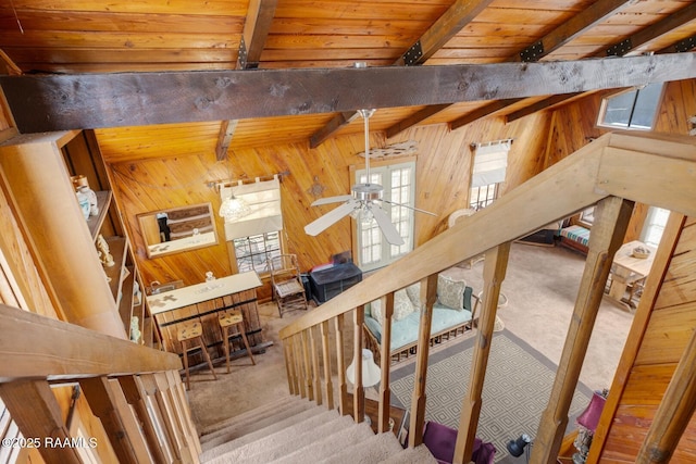 stairs featuring carpet, wood walls, and beamed ceiling