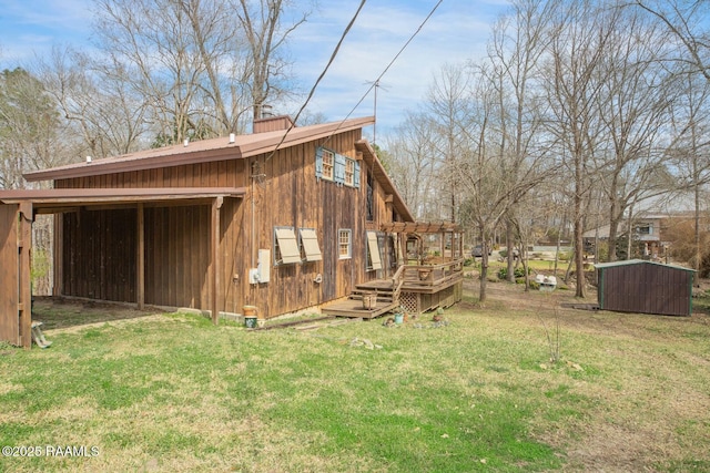 view of side of home with a storage shed, an outdoor structure, a yard, a wooden deck, and a chimney