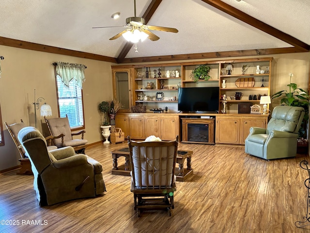 living room featuring a textured ceiling, vaulted ceiling with beams, a ceiling fan, baseboards, and light wood-type flooring