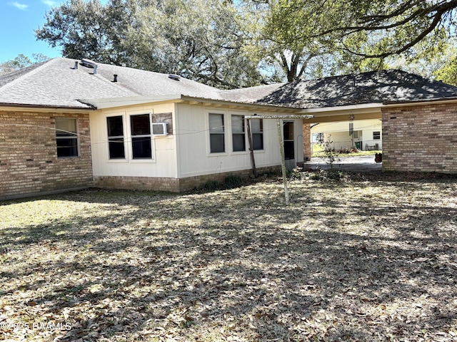 rear view of property featuring brick siding and roof with shingles