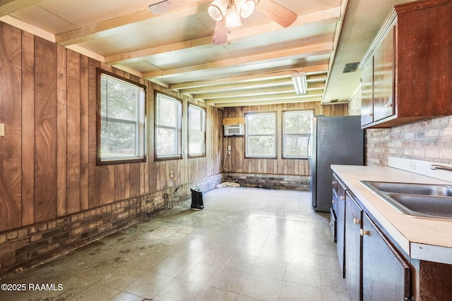 1410 S Chataignier Rd, Ville Platte, LA 70586 - kitchen with wooden walls, beamed ceiling, light countertops, ceiling fan, and freestanding refrigerator