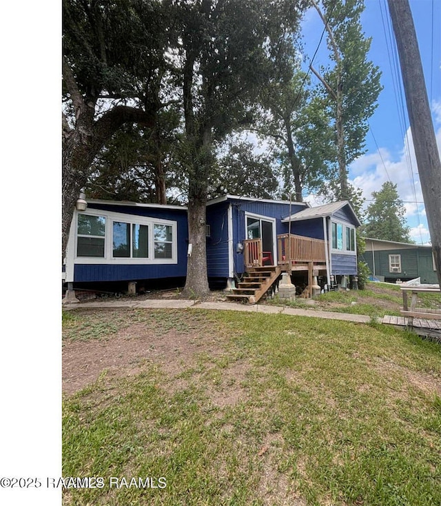 manufactured / mobile home featuring a front lawn and a wooden deck