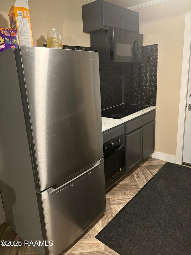 kitchen featuring baseboards, light countertops, backsplash, and black appliances