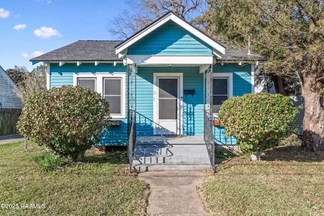 view of front of property featuring covered porch, a front lawn, and fence