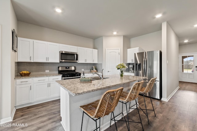 kitchen with appliances with stainless steel finishes, wood finished floors, and decorative backsplash