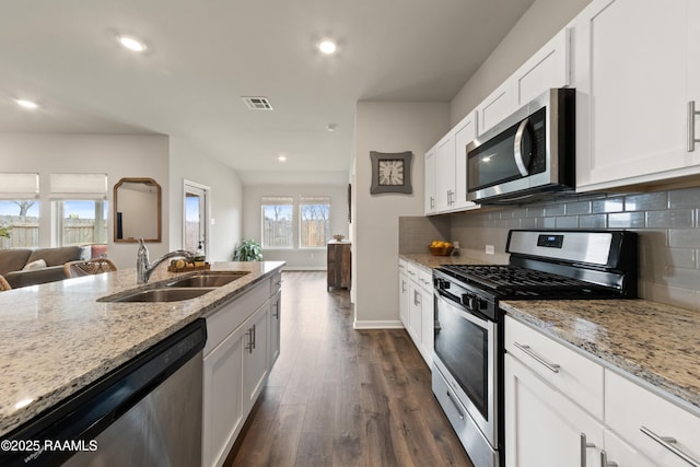 kitchen featuring appliances with stainless steel finishes, a sink, light stone counters, and decorative backsplash