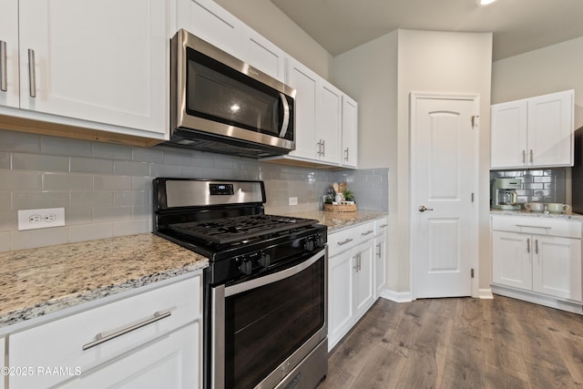 kitchen with light stone counters, dark wood-style flooring, stainless steel appliances, tasteful backsplash, and white cabinets