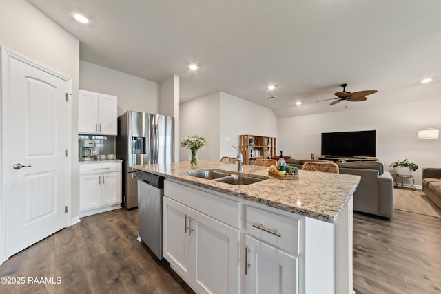 kitchen featuring dark wood-style floors, appliances with stainless steel finishes, a sink, and a center island with sink