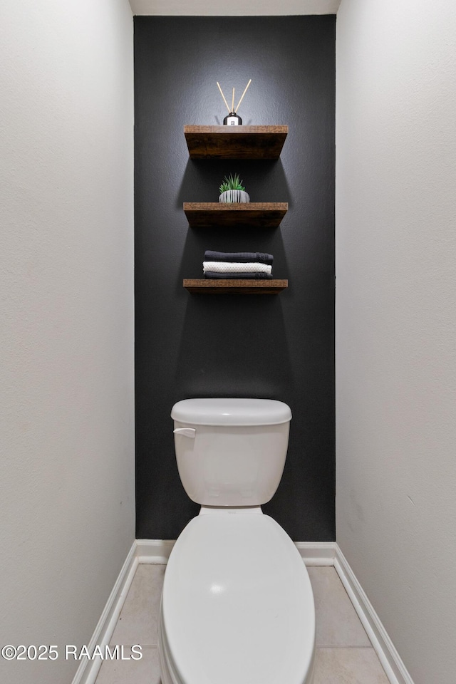 bathroom with toilet, baseboards, and tile patterned floors