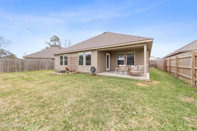 rear view of house featuring a patio area, a lawn, a fenced backyard, and roof with shingles