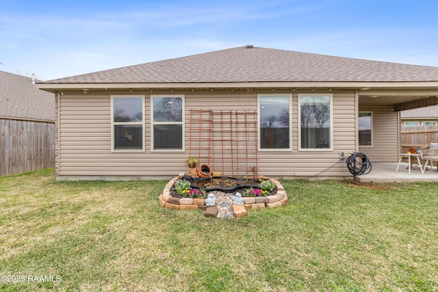 back of house featuring a fenced backyard, roof with shingles, a lawn, and a patio