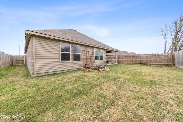 rear view of property featuring a yard, roof with shingles, and a fenced backyard