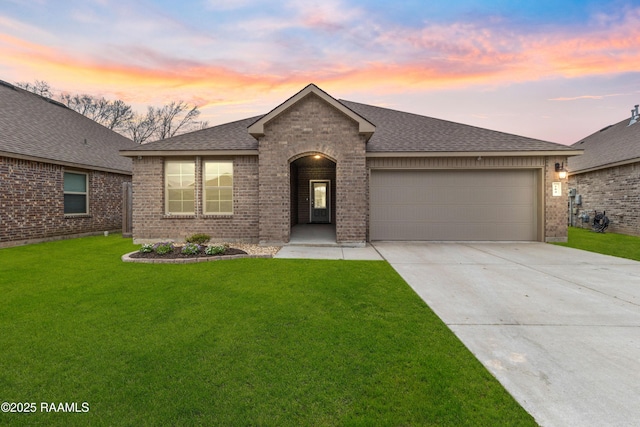 ranch-style home with a garage, a shingled roof, a lawn, concrete driveway, and brick siding