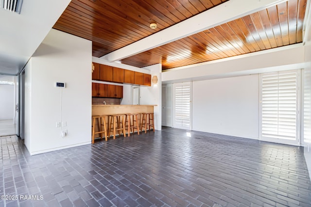 unfurnished living room featuring wooden ceiling, beamed ceiling, brick floor, and visible vents