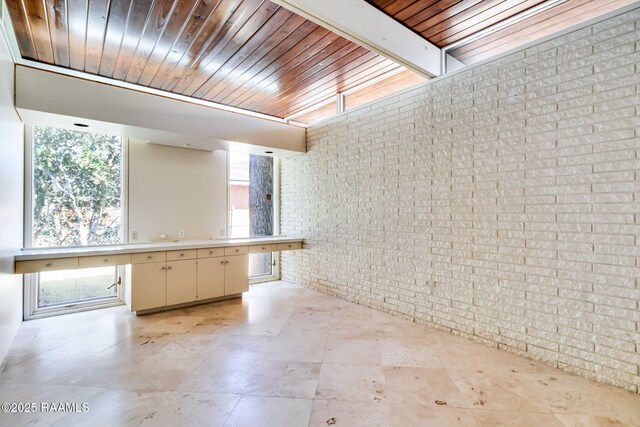 empty room featuring wood ceiling and brick wall