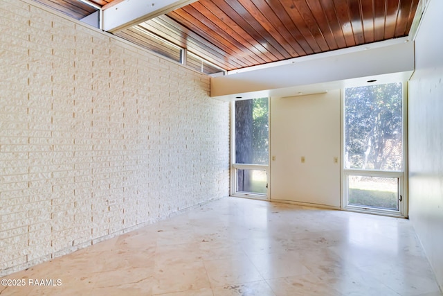 empty room featuring wood ceiling and brick wall