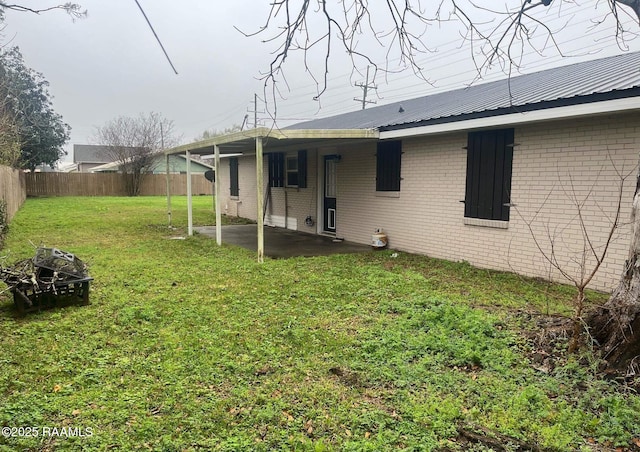 back of property featuring brick siding, a yard, a patio area, metal roof, and a fenced backyard