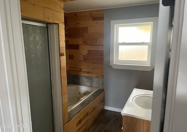 bathroom with wood finished floors, a shower with shower door, a whirlpool tub, vanity, and wood walls