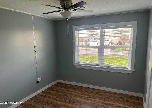 spare room featuring dark wood-style floors, ornamental molding, a ceiling fan, and baseboards