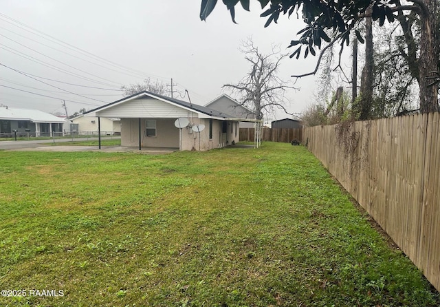 view of yard with a fenced backyard and a carport