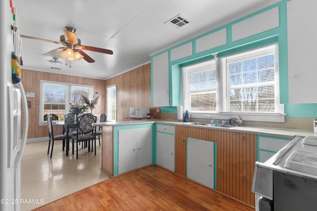 kitchen with visible vents, a ceiling fan, a sink, freestanding refrigerator, and a peninsula