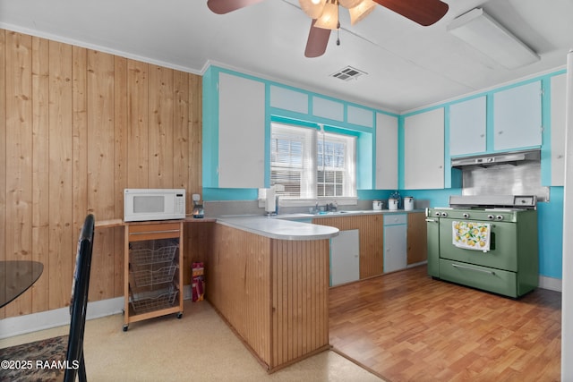 kitchen featuring a ceiling fan, white microwave, visible vents, stainless steel range with gas cooktop, and under cabinet range hood