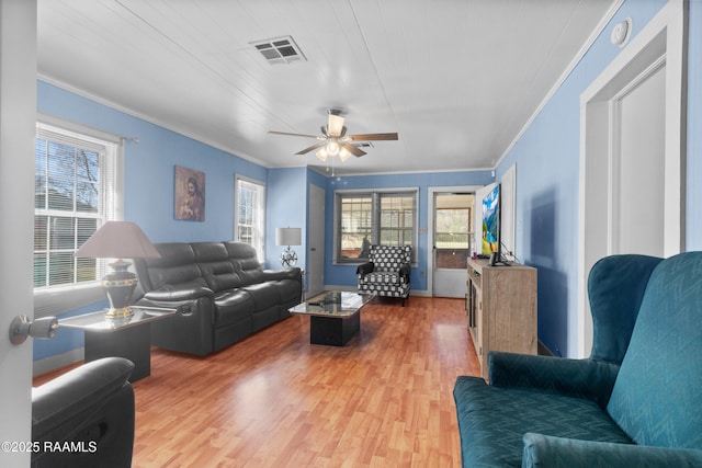 living room with a ceiling fan, light wood-style floors, visible vents, and ornamental molding