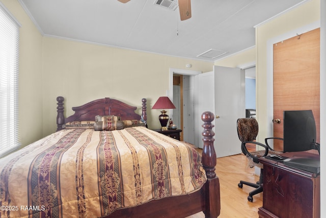 bedroom featuring visible vents, wood finished floors, crown molding, attic access, and ceiling fan