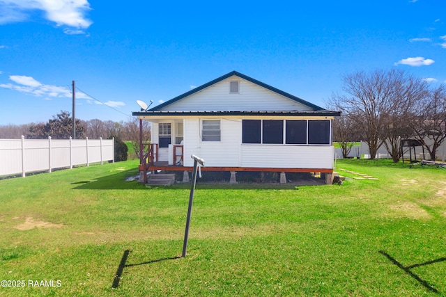 back of property featuring a lawn and fence