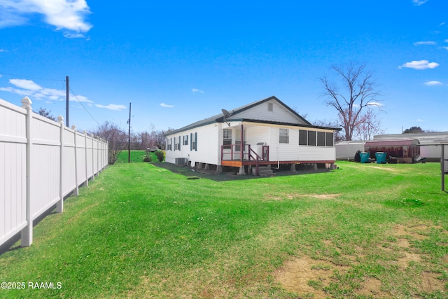 rear view of house featuring a lawn and fence