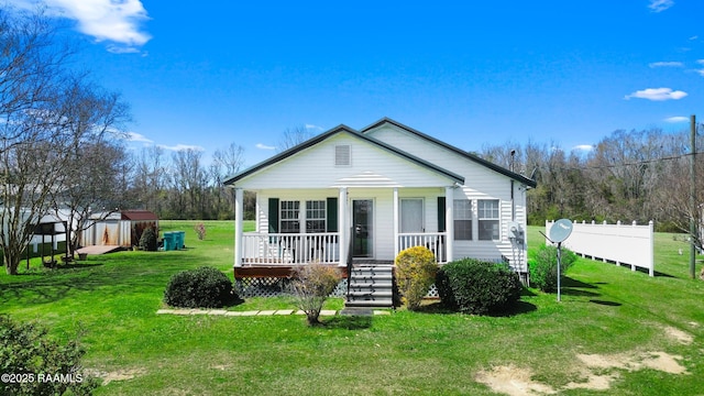 view of front of home featuring a front yard, an outbuilding, fence, a porch, and a storage unit