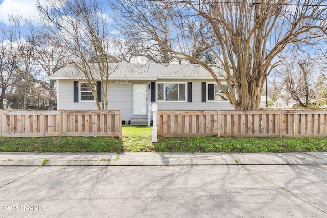 view of front of property with entry steps, a fenced front yard, and roof with shingles