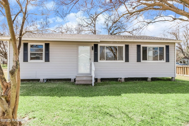 view of front facade featuring entry steps, roof with shingles, and a front yard