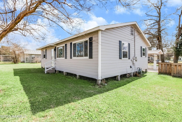 view of property exterior with entry steps, fence, and a lawn