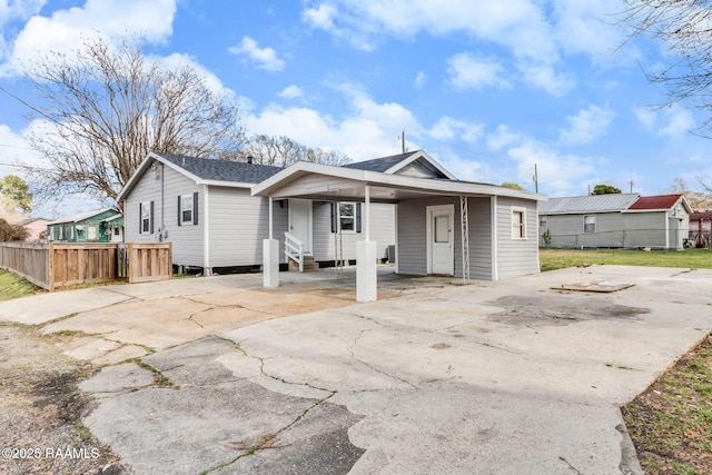 view of front facade featuring a shingled roof, entry steps, concrete driveway, and fence