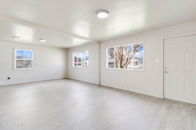 spare room with light wood-style floors, visible vents, and baseboards