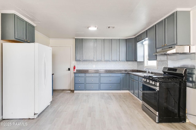 kitchen featuring light wood finished floors, stainless steel range with gas stovetop, freestanding refrigerator, and under cabinet range hood