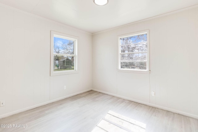 spare room with wood finished floors, a wealth of natural light, and crown molding