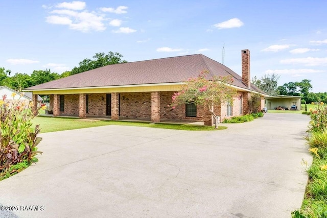 view of front of home with driveway, a front yard, a chimney, and brick siding