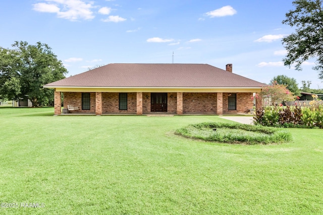 rear view of house with brick siding, a lawn, and a chimney