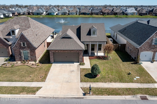 view of front of property featuring brick siding, a water view, a residential view, driveway, and a front lawn