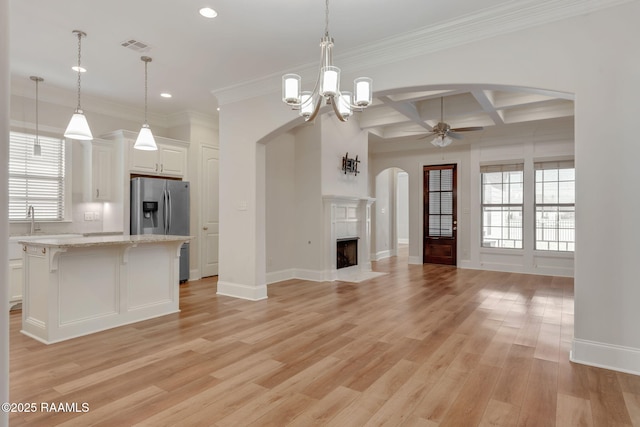 kitchen featuring arched walkways, a premium fireplace, coffered ceiling, light wood-type flooring, and stainless steel fridge with ice dispenser