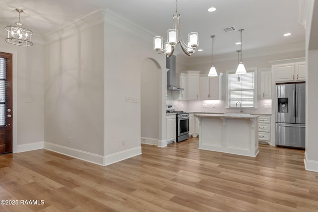 kitchen featuring a chandelier, wall chimney exhaust hood, appliances with stainless steel finishes, and visible vents