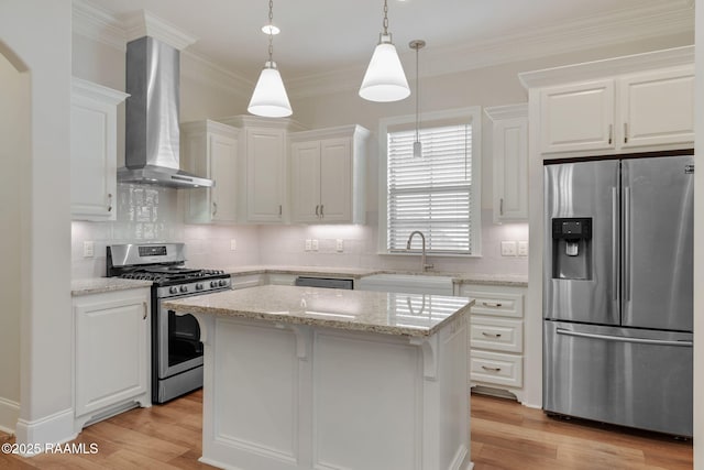 kitchen with wall chimney range hood, appliances with stainless steel finishes, light wood-style floors, and a sink