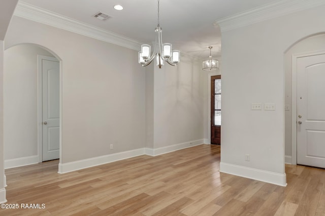 spare room with arched walkways, baseboards, crown molding, light wood-type flooring, and a chandelier