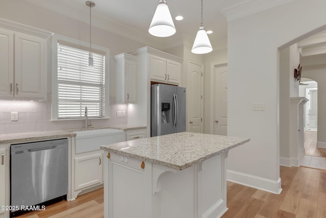 kitchen featuring ornamental molding, appliances with stainless steel finishes, a sink, and light wood-style flooring