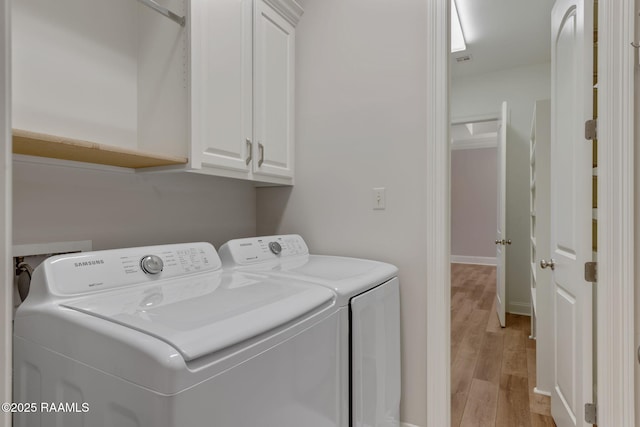 laundry area with light wood-type flooring, cabinet space, and independent washer and dryer