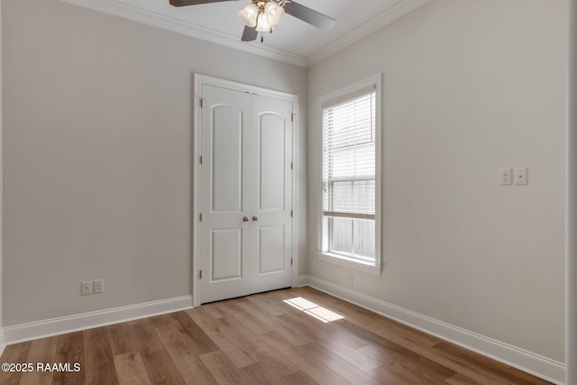 interior space with a ceiling fan, baseboards, ornamental molding, and wood finished floors