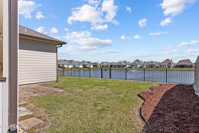 view of yard featuring a water view, a fenced backyard, and a residential view