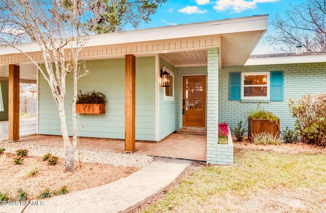 property entrance with brick siding and a porch